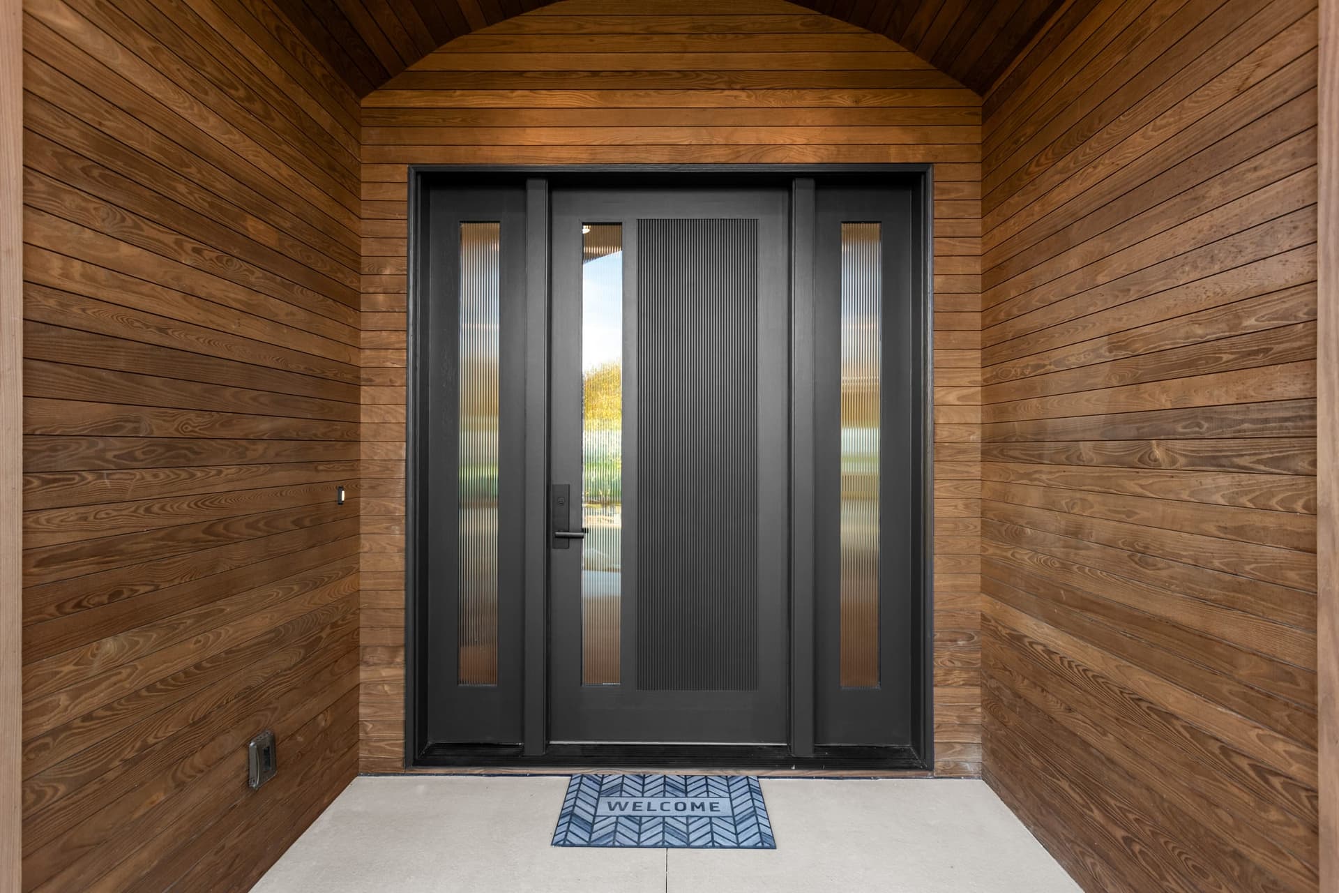 Barrel-vault entry vestibule with warm wood plank ceiling, reeded glass front door, and smart lock