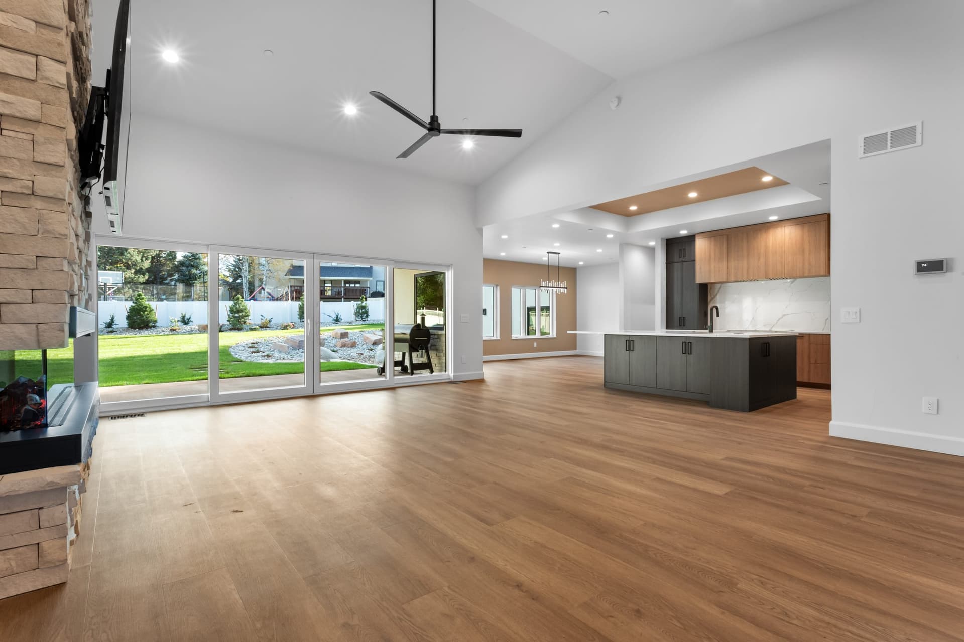 Great room to kitchen — vaulted ceiling, open floor plan, sliding glass doors, kitchen island visible