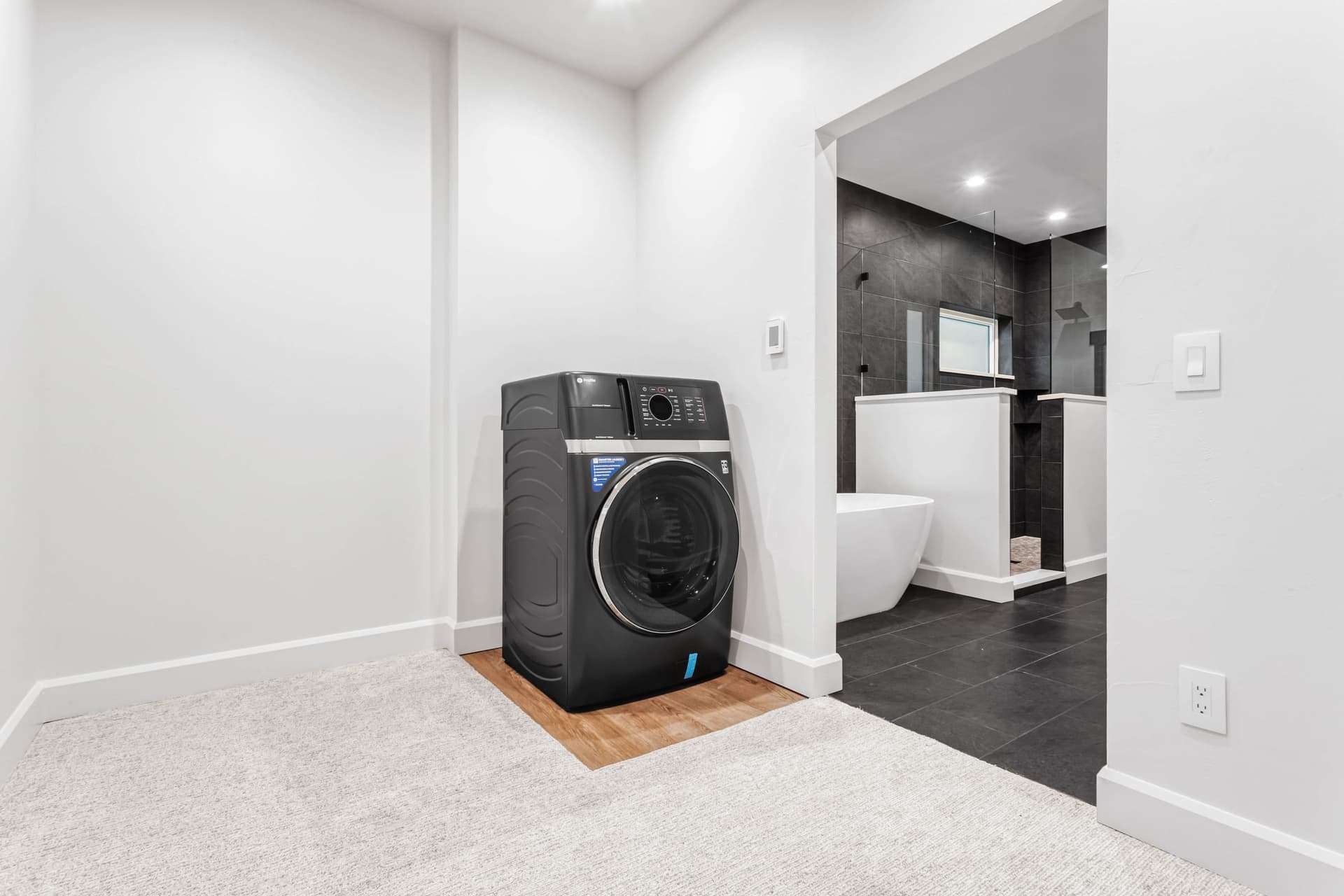 Master suite — integrated laundry nook, freestanding soaking tub, and frameless glass walk-in shower