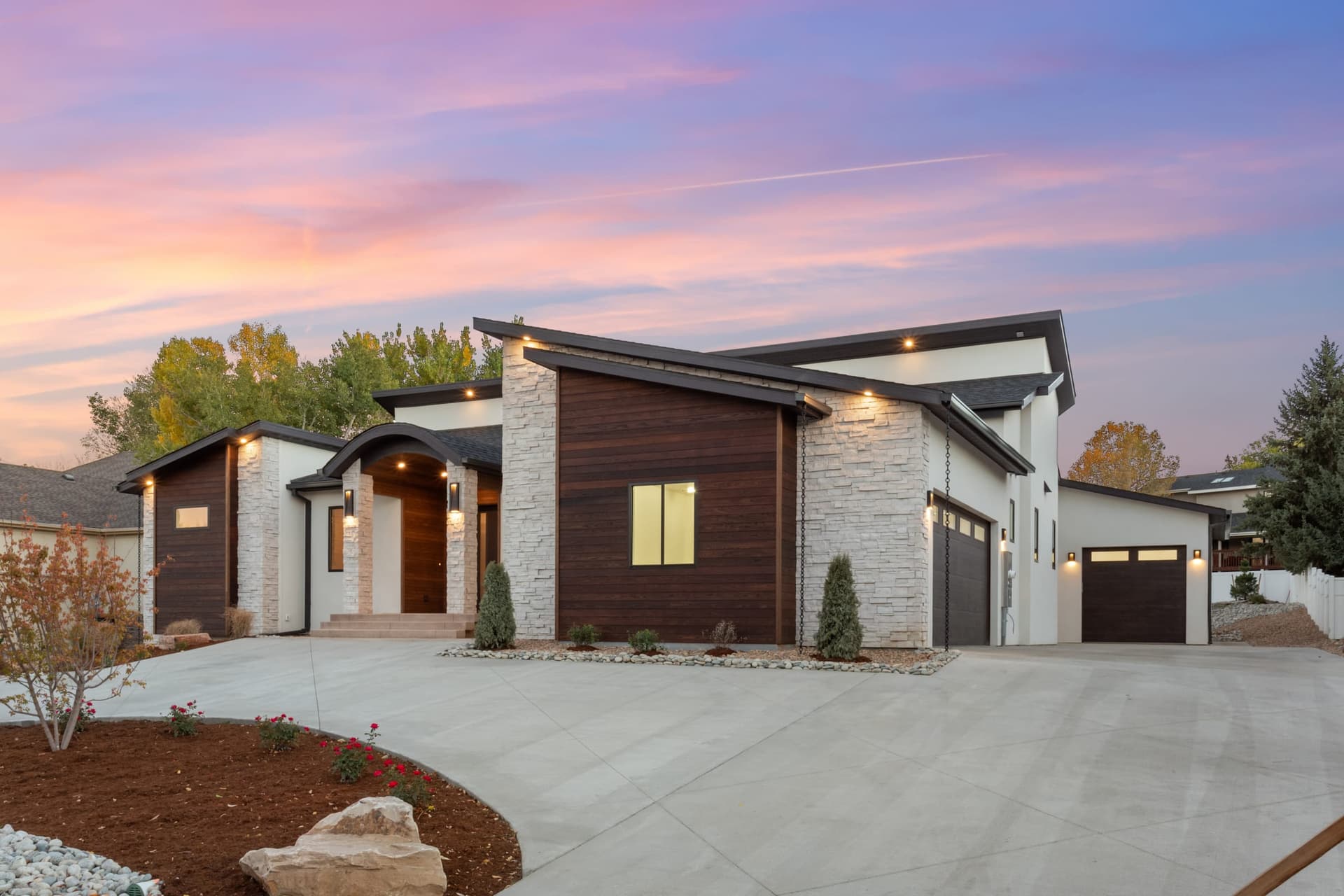 Ranch home exterior at twilight with an arched entry and stone columns