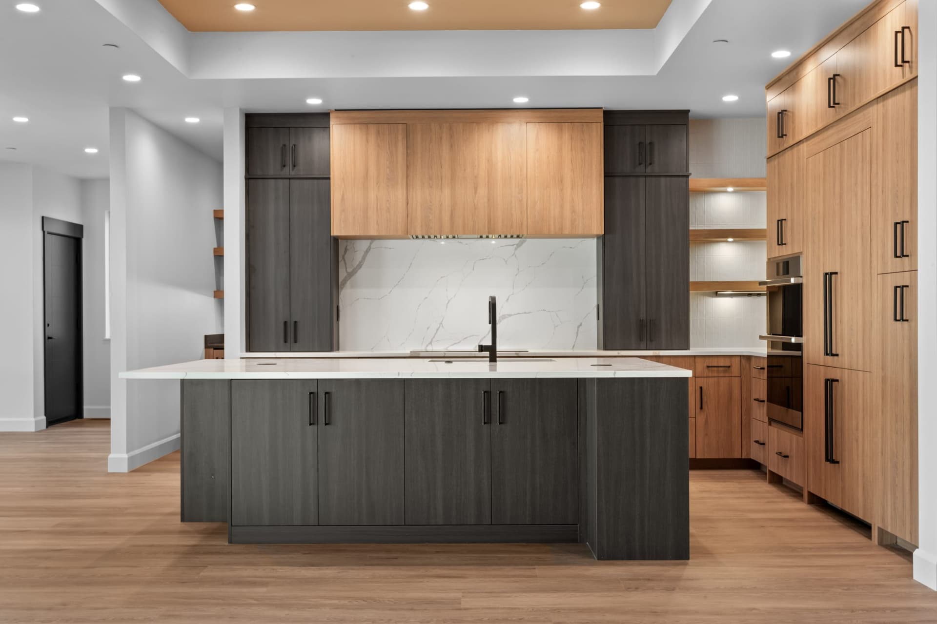 Kitchen island beneath a wood-trimmed range hood with dark and wood cabinetry