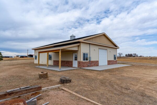 Exterior image of a completed new build barn with a porch, garage space, commercial garage door, and interior living space.