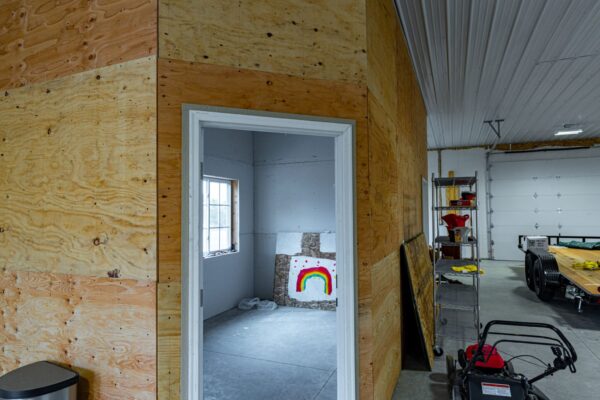 New build large garage in barn space with interior room, commercial garage doors, and natural light.