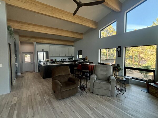 Open floor plan, exposed beams, large windows, hardwood floors creating a comfortable living space.