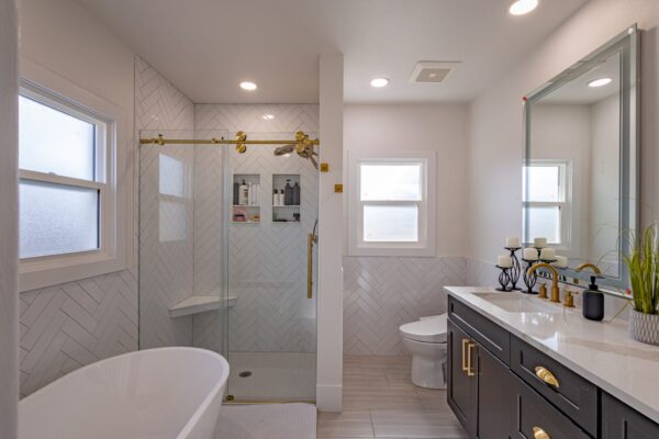 Elegant bathroom with a modern tub, glass shower with built-in storage, and a sink with a countertop and storage.