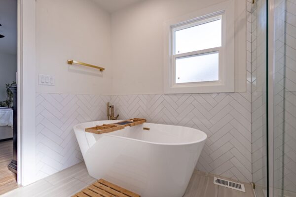 Modern new build with elegant features, a sleek tub, hardwood floors, and a spacious glass shower.