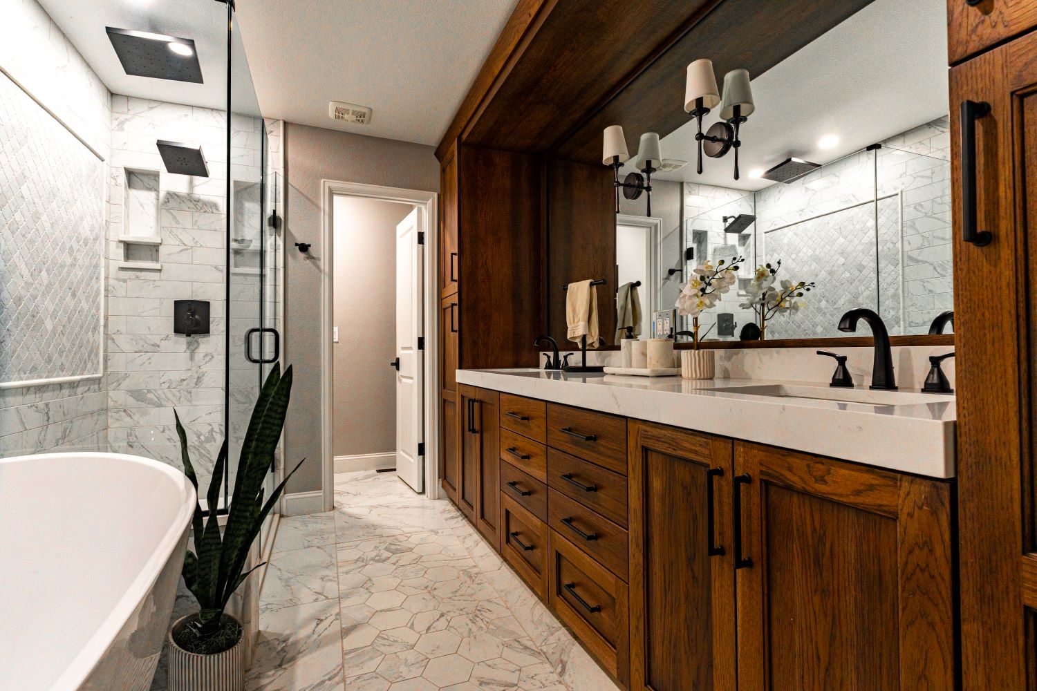 Elegant, functional bathroom in a renovated home with a modern tub, glass shower, wood cabinetry, and stylish lighting.