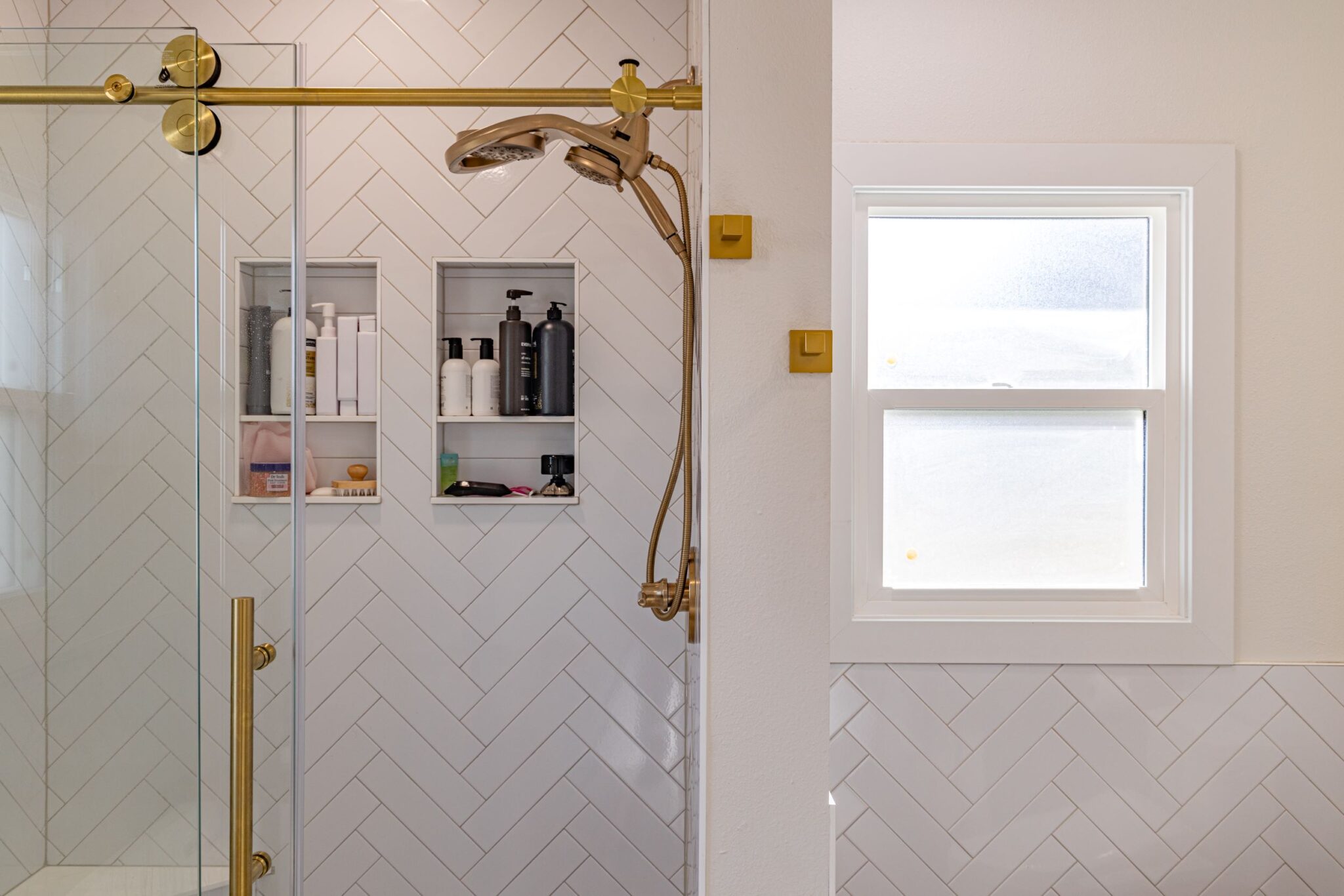 Renovated bathroom with elegant tiling, features, and built-in shower storage.